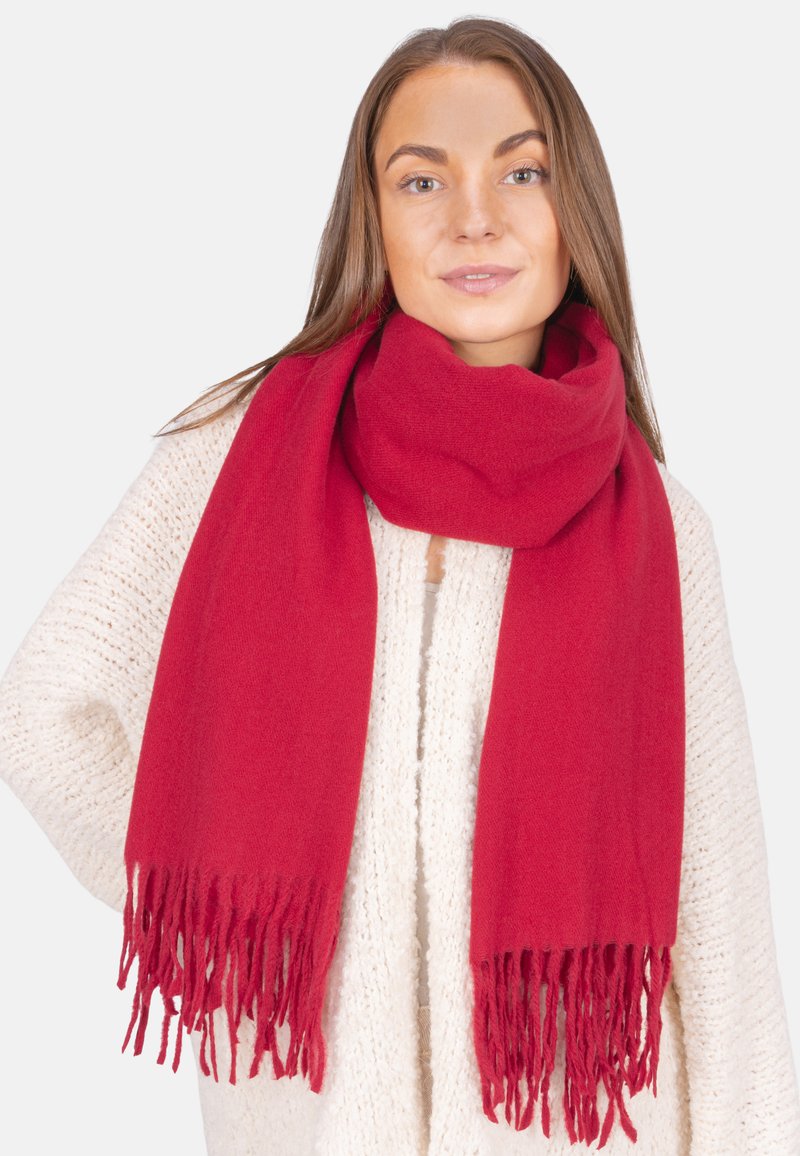 Roter Schal mit fransigen Enden, aus weichem Material, locker um den Hals getragen über einem strukturierten cremfarbenen Pullover.