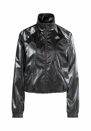 Czarna, błyszcząca kurtka typu cropped z wysokim kołnierzem, zapinana na zamek, z bocznymi kieszeniami i perforowanymi detalami. Na piersi znajduje się logo adidas.