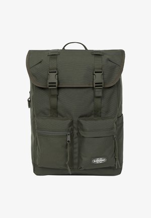 Donkergroene rugzak met klep, twee ritszakken aan de voorkant en verstelbare banden. Gemaakt van duurzaam materiaal met een logodetail onderaan.