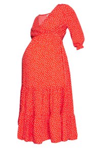 Vestido de maternidad rojo con lunares blancos, escote en V, mangas largas y falda en capas. Confeccionado con tejido ligero para mayor comodidad.