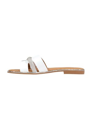 Sandalia plana deslizante con tiras blancas cruzadas y un adorno de pedrería plateada, suela marrón claro y tacón bajo de madera.