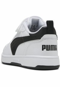 Sneaker blanc avec une bande noire, tige en cuir, col rembourré et semelle en caoutchouc texturé. Présente un logo "PUMA" noir sur le talon.