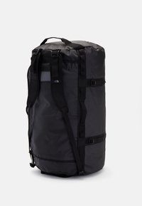 Black duffel bag with sturdy fabric, adjustable straps, and side buckles. Features a mesh pocket on one side for additional storage.