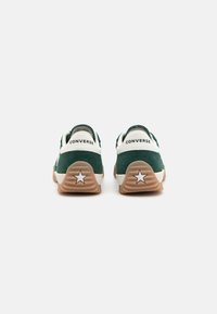 Zielone zamszowe sneakersy z białymi akcentami, wyposażone w gumową podeszwę i logo gwiazdy na pięcie. Niski profil z wyściełanym kołnierzem.