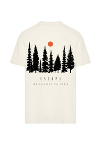 Cream t-shirt featuring a black forest silhouette and an orange sun graphic. Text below reads "ESCAPE AND DISCOVER THE WORLD."