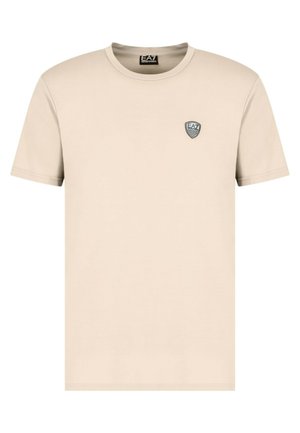 T-shirt in cotone beige con maniche corte, scollo rotondo e un piccolo logo ricamato in bianco e nero sul petto.