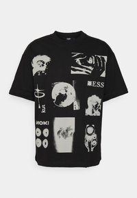 Svart bomullströja med olika grafiska tryck i vitt. Rektangulär design, korta ärmar, rund halsringning, med flera konstnärliga motiv och text.