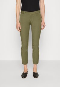 Olivgröna skräddarsydda byxor med slim fit, med två framfickor och en slät textur; ihopparade med svarta platta skor.