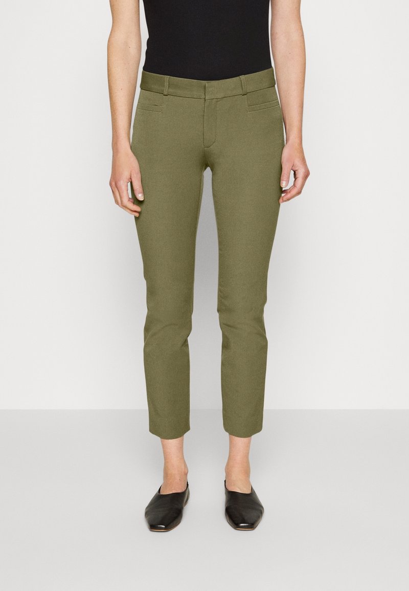 Olivgröna skräddarsydda byxor med slim fit, med två framfickor och en slät textur; ihopparade med svarta platta skor.