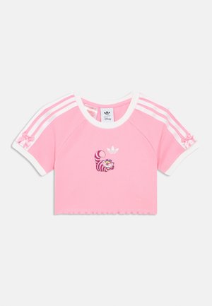 T-shirt rosa crop top com textura canelada, detalhes brancos e riscas Adidas em rosa e branco. Apresenta um design impresso do Gato de Cheshire.