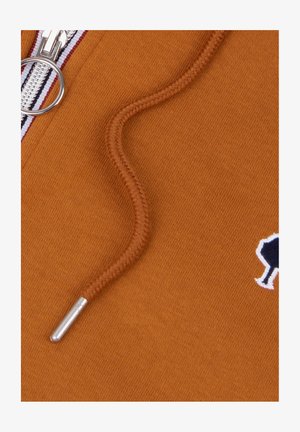 Close-up of orange fabric with a braided drawstring, metal aglet, silver zipper, and a small black and white embroidered tree logo.