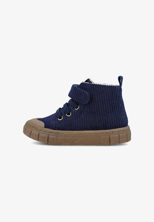 Zapatilla alta de corduroy en color marino con suela de goma marrón, parte delantera con cordones, ojales dorados y una correa de Velcro para mayor soporte.