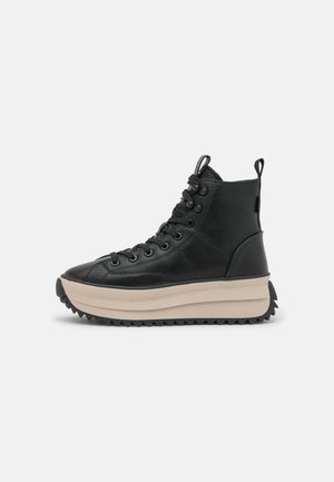 Czarne skórzane wysokie sneakersy z grubą beżową podeszwą platformową i wiązaniem z przodu na białym tle.