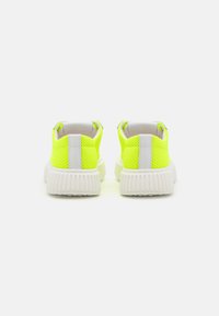 Baskets en maille jaune néon avec une stripe blanche au niveau du talon et une semelle blanche texturée. Design léger avec un dessus respirant.
