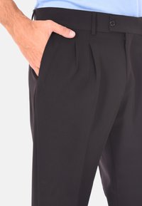 Pantaloni neri plissettati realizzati in tessuto morbido, dotati di chiusura con zip, bottone e tasche laterali, con una vestibilità su misura.