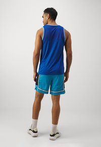Top deportivo azul con acentos en azul claro combinado con pantalones cortos turquesa que tienen ribetes en negro y blanco, textura de malla y un diseño deportivo.