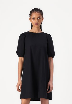 Black cotton dress with short puff sleeves, round neckline, and a loose fit. Features a knee-length hem and smooth texture.