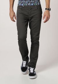 Donkergrijze jeans van katoen, met een slim fit, vijf zakken en gedragen met zwart-witte sneakers. Katoenen geruite overhemd zichtbaar.