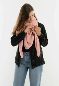 Roze gebreide sjaal met een gestructureerd patroon, om de nek gedrapeerd, vastgehouden met een bruine accent-sluiting. Draagt het met een zwarte spijkerjas en blauwe jeans.