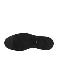 Semelle de chaussure en caoutchouc noir avec un bout lisse et arrondi, une texture adhérente et des rainures horizontales distinctes. Présence d'un petit détail évoquant le drapeau italien.