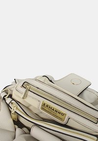 Borsa a tracolla in pelle bianca con finiture in oro, dotata di più scomparti con zip, un'etichetta con il logo e una finitura testurizzata con cuciture a contrasto.