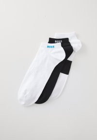 Trois paires de chaussettes mi-mollet en coton noir et blanc. Chaque chaussette arbore le logo "BOSS" en couleurs contrastées sur le bord.