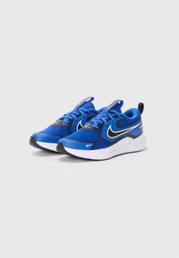 Scarpe sportive blu con tomaia in rete, dettagli neri e suola bianca. Presentano un logo swoosh prominente e un design con allacciatura.