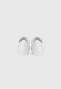 Hvide sneakers med en glat læderfinish, rund tå og en blank cremefarvet hældetalje. Karakteriseret ved minimal syning og en gummisål.
