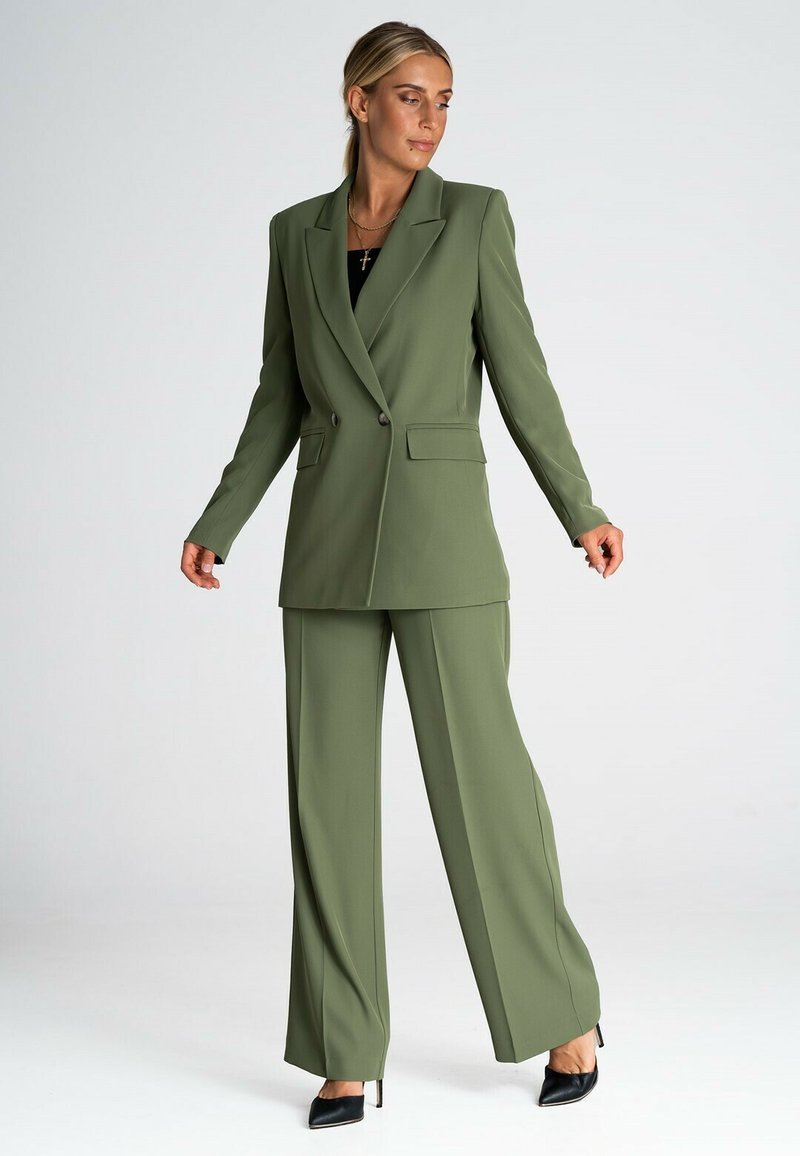 Zielono-oliwkowa marynarka i dopasowane szerokie spodnie, wykonane z gładkiego materiału. Marynarka ma dwa guziki, klapy typu notch i boczne kieszenie.