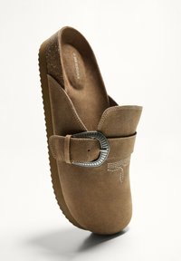 Rjavi gamušasti klompi z detajlom s sponko, teksturirano notranjo podlago in gumijastim podplatom, z vdrtimi akcenti. Preprost dizajn brez hrbta.