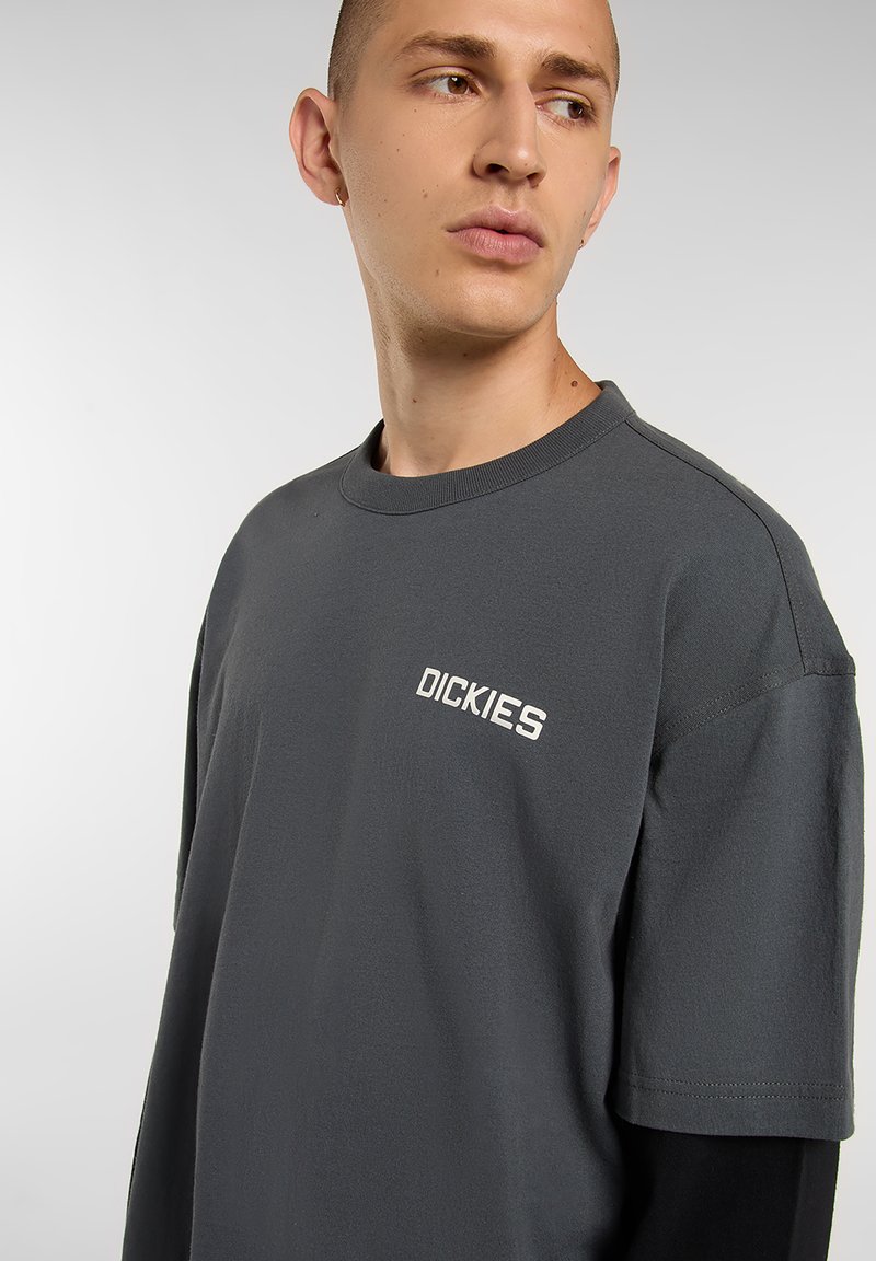 Dark gray cotton t-shirt with a crew neck and short sleeves, featuring white "DICKIES" branding on the left chest. Smooth texture.