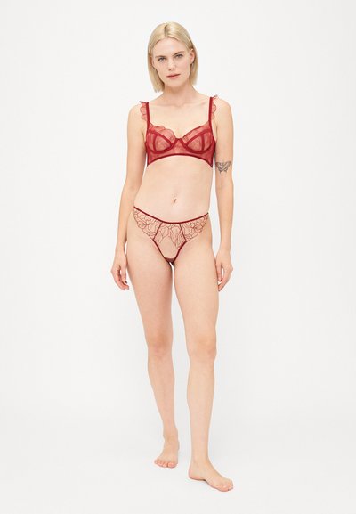 Rode kant lingerie set met een balconette beha met gerimpelde randen en een bijpassende string met een bloemenpatroon en transparante textuur.
