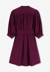 Robe ceinturée, longueur genoux, de couleur violet foncé, présentant un dos froncé, de longues manches bouffantes et des poignets à boutons. Fabriquée en tissu lisse.