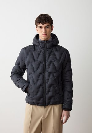 Giubbotto imbottito nero con cappuccio, caratterizzato da un motivo geometrico, chiusura frontale con zip e tasche laterali. Il materiale sembra liscio e leggero.