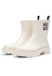 Witte rubberen enkellaarzen met een dikke, geribbelde zool, voorzien van een zwart "HUGO" logo aan de zijkant en trekloopjes voor gemakkelijke aantrek.