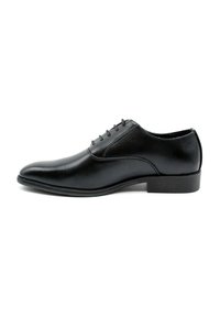 Chaussure de costume en cuir noir avec une finition lisse, bout pointu et six œillets pour les lacets. Présente une semelle en caoutchouc robuste et des détails de couture minimalistes.