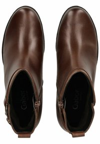 Bottines en cuir marron avec une texture lisse, des fermetures éclair sur les côtés, un bout arrondi et des détails de logo à l'intérieur.