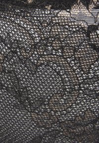 Schwarzer Spitzenstoff mit einem floralen Muster, das aus komplizierten offenen Geweben und einer glatten Textur besteht, über einem hautfarbenen Hintergrund geschichtet.