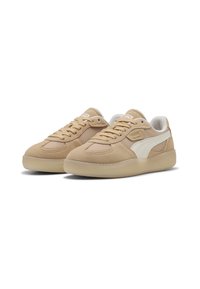 Beige suede sneakers with white accents, round toe, and flat lace-up design. Features a textured upper and a rubber sole for grip.
