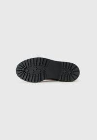 Semelle de botte en caoutchouc noir avec un motif de crampons profond et marquage de taille 37 sur fond blanc uni.