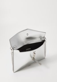 Borsa a tracolla metallica argento con design geometrico, chiusura a scatto e tracolla in argento. L'interno presenta una fodera nera e una tasca.