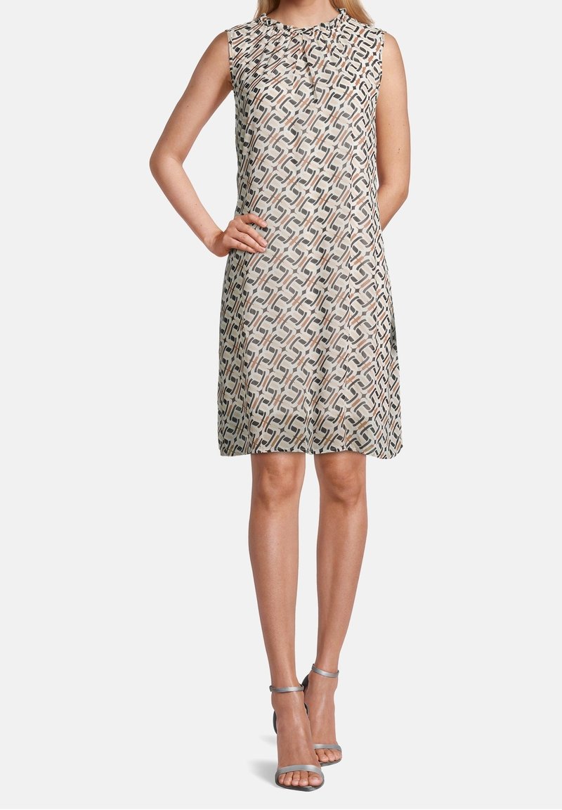 Bezramínková šaty v krémové barvě s složitým geometrickým vzorem v hnědé a černé. Mají kulatý výstřih a uvolněný střih.