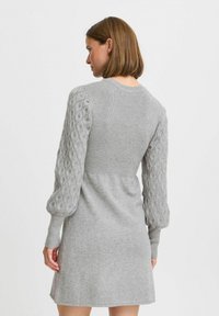 Abito grigio a maglia con corpino a coste e maniche a palloncino testurizzate. Tessuto morbido, design a lunghezza intermedia, dettagli sottili con vestibilità rilassata.