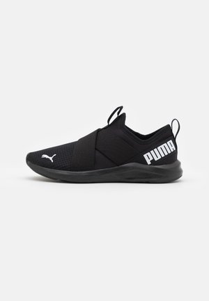Sort slip-on Puma sneakers med elastiske krydsede stropper, hvid Puma-logo på tåen og fed "PUMA" tekst på hælen mod en ens hvid baggrund.