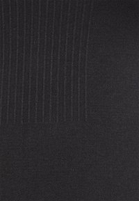 Tissu noir texturé avec un motif côtelé vertical sur le côté gauche et un tricot fin et lisse sur le côté droit.