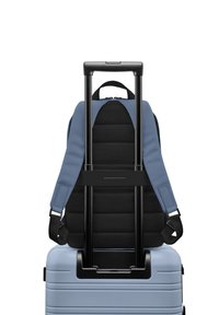 Un sac à dos bleu fixé sur une valise rigide bleu clair, dotée d'une silhouette télescopique, de straps rembourrés et d'un panneau arrière texturé.