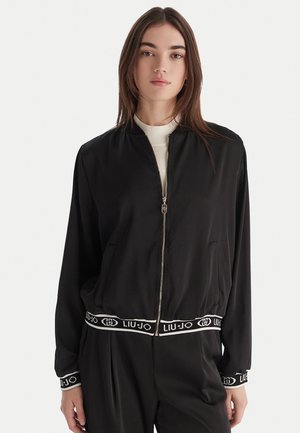 Giubbotto bomber nero in tessuto elegante con zip frontale, polsini a coste e vita con logo Liu Jo a contrasto.