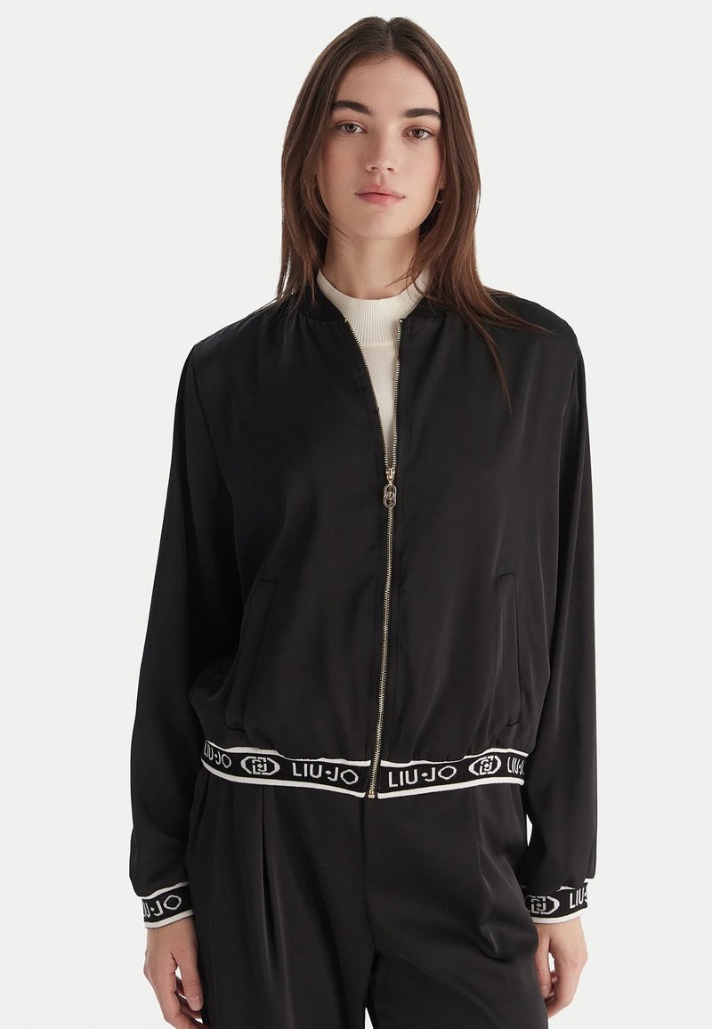 Giubbotto bomber nero in tessuto elegante con zip frontale, polsini a coste e vita con logo Liu Jo a contrasto.