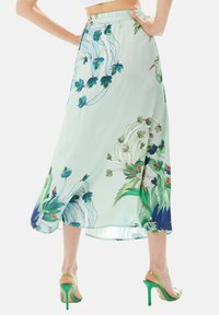 Floral long skirt in light mint green fabric, featuring blue and green plant designs, a gathered waistband, and a side slit.