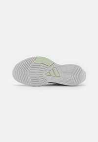 White athletic shoe sole with a textured rubber surface, featuring green accents and a three-stripe logo design.